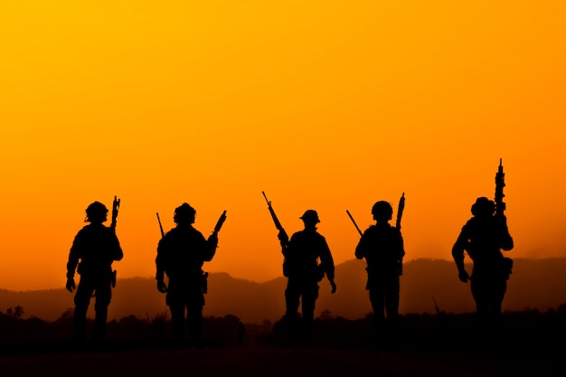 silhouette of Soldier team in sunset sky. Soldier with machine gun patrolling