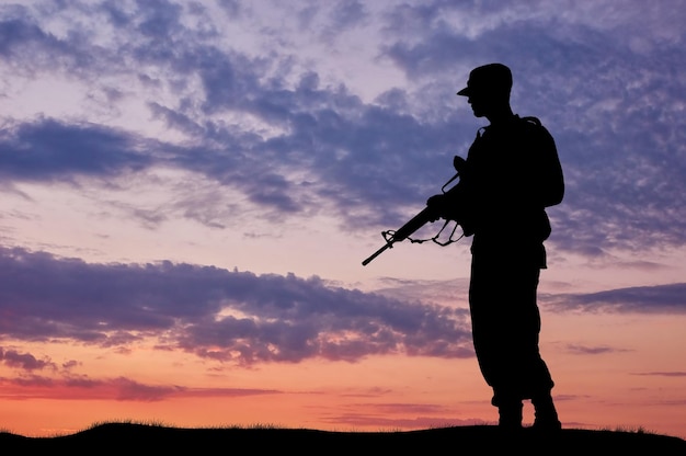 Silhouette of soldier with a gun on a background of sunset