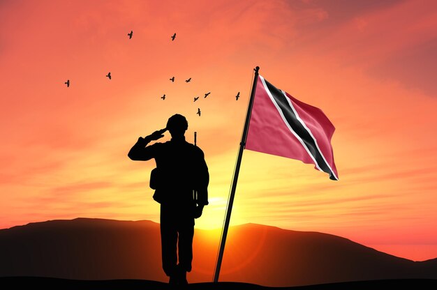 Foto silhouette di un soldato con la bandiera di trinidad e tobago in piedi contro il tramonto o l'alba