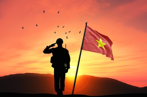 Photo silhouette of a soldier with the vietnam flag stands against the background of sunset or sunrise