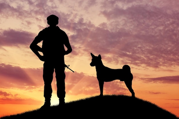 Silhouette of soldiers with weapons and dogs on the top at sunset