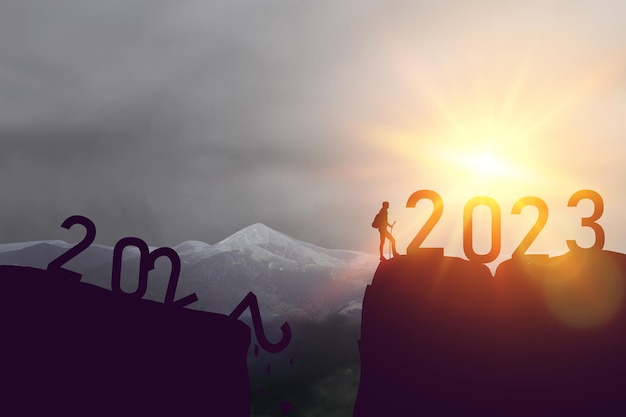 Silhouette sport man with  and  number new year on sunset sky at top of mountain abstract background...