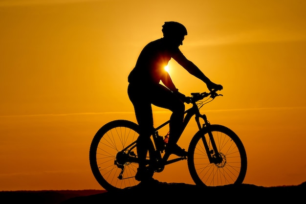 Silhouette di un ciclista sportivo nel casco su una bici