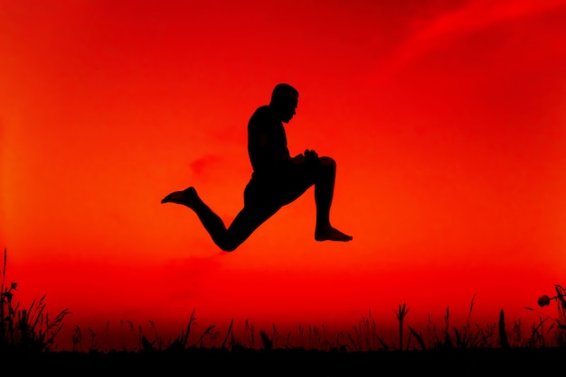 Силуэт спортивный человек прыгает высоко в природе