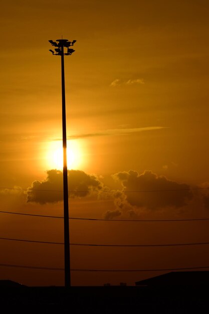 Silhouette street light against orange sky