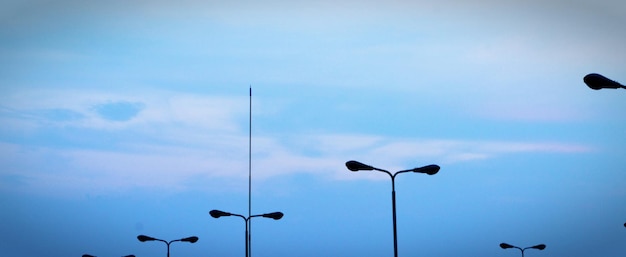 Photo silhouette street lights against cloudy sky