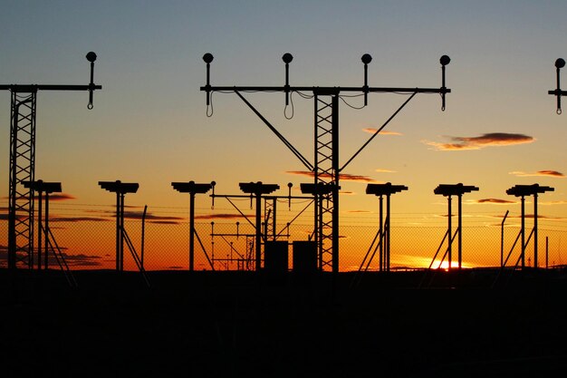 Photo silhouette street lights on field against orange sky