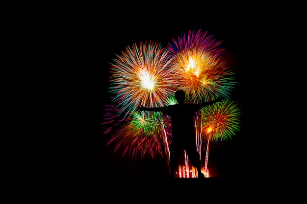 Photo silhouette successful man at the peak, beautiful colorful fireworks display on the sea beach.