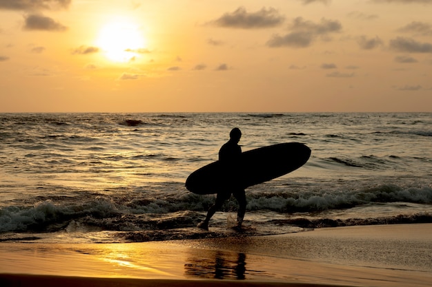 Silhouette Surfer uit de oceaan bij zonsondergang