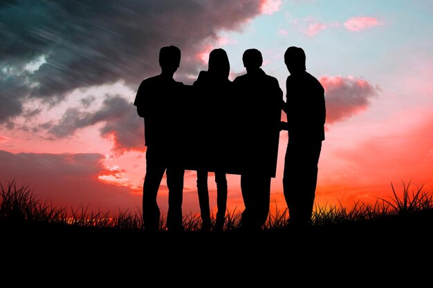 Silhouette of team holding a poster against red sky over grass