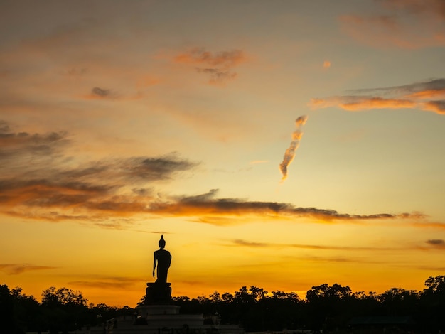 タイのウォーキングブッダ像と黄金の夕暮れの夕方の空の下でのシルエットテクニック