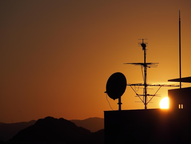 Silhouette of telephone pole against sky during sunset