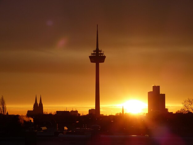 Silhouette of tower and buildings against sky during sunset