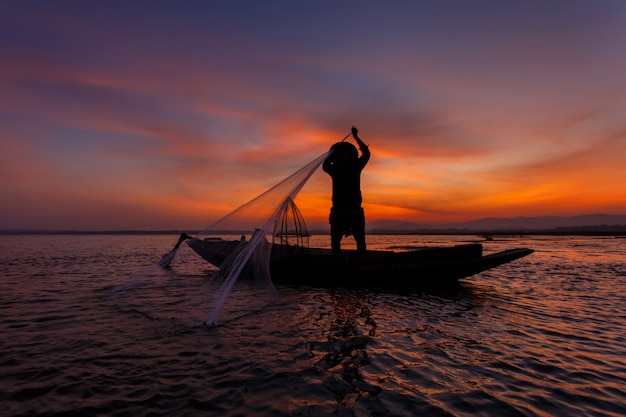 Siluetta dei pescatori tradizionali che gettano il lago del inle di pesca netta a tempo di alba, myanmar