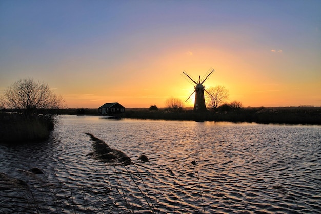 Silhouette traditional windmill against sky during sunset