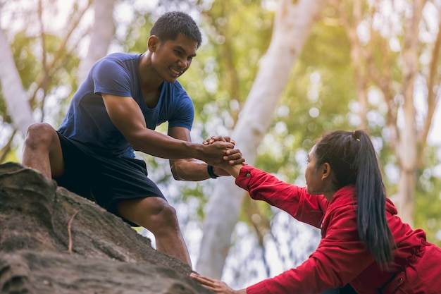 Photo silhouette of trail runner with hand helping each other hike up a mountain top together