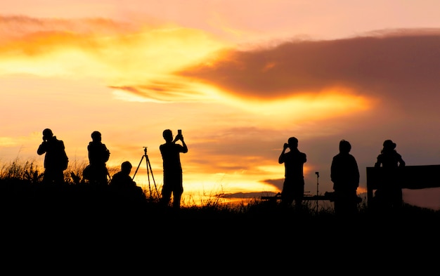 Silhouette of traveler taking picture of landscape during sunrise.