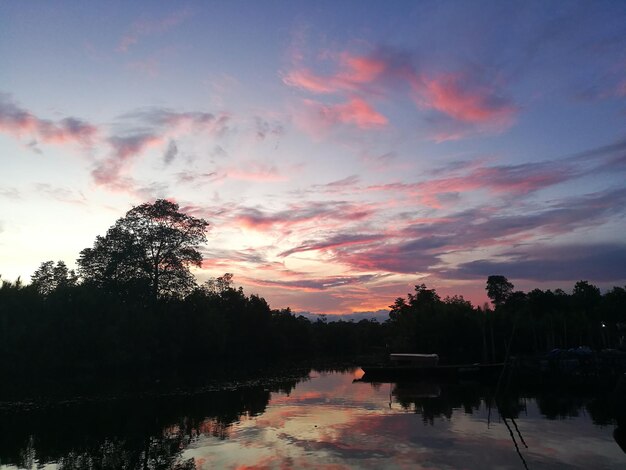 Silhouette trees by lake against sky during sunset