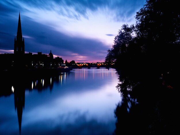 Silhouette trees by lake against sky at sunset