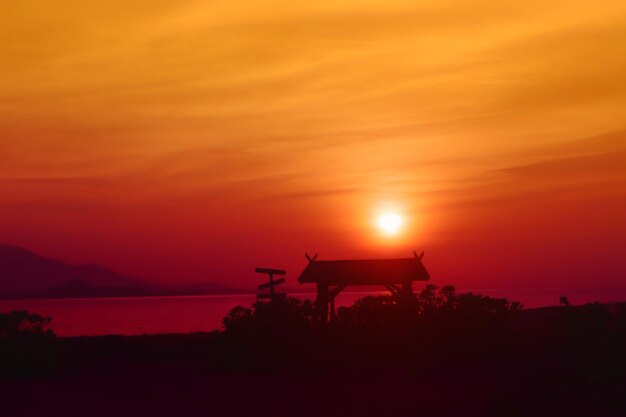 Silhouette trees by sea against sky during sunset