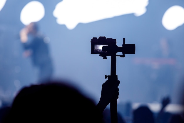 Silhouette of tripod with camera on concert.