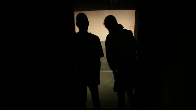 Silhouette of two other men looking out the window footage two friends in front of the window the
