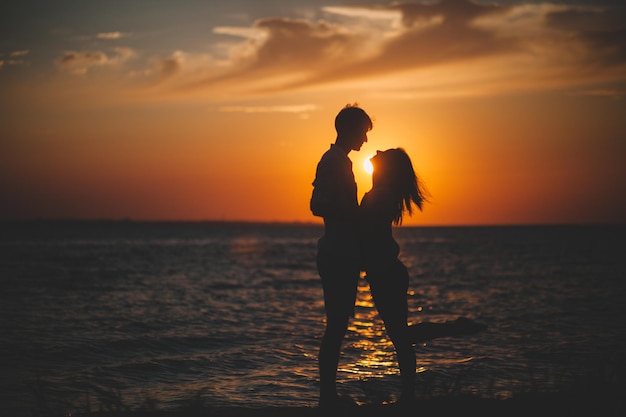 Photo silhouette of two people holding hands against the sea