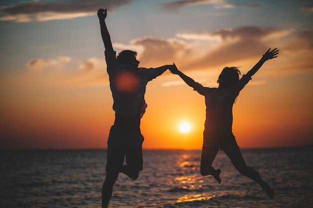 Silhouette of two people holding hands against the sea