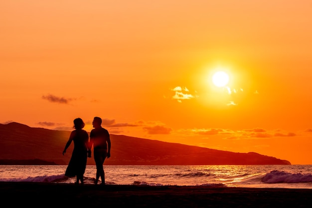 Silhouette of two persons in sunset love and dancing having fun