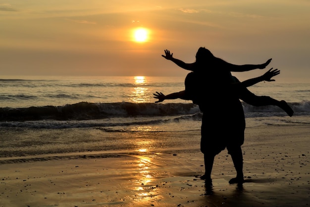 日没のゴールデンアワーで海岸で遊ぶ2人の女性のシルエット