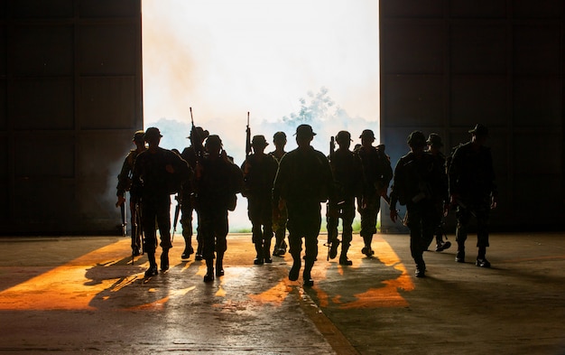 silhouette of unrecognized soldiers with rifle walk through smoke