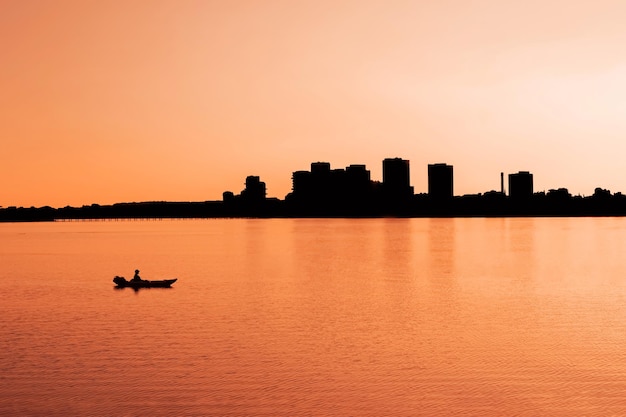 Silhouette urban landscape and kayaking on the sea at sunset