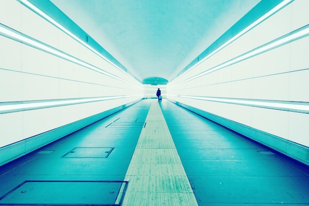 Silhouette walking in blue illuminated tunnel