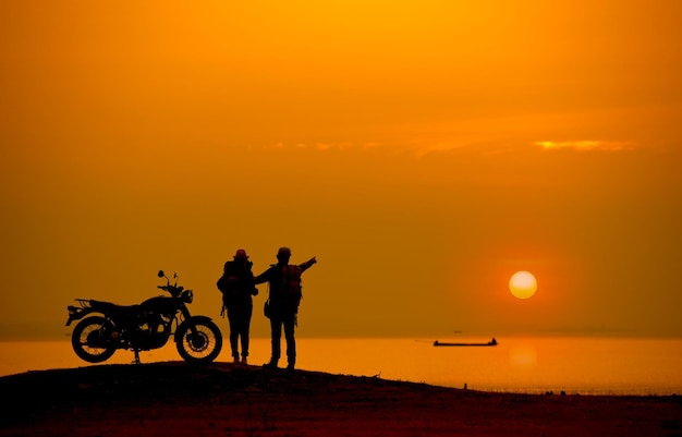 Foto silhouette wandelaars op een motorfiets tegen de hemel tijdens de zonsondergang