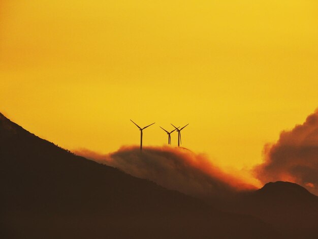 Photo silhouette of wind turbine against sky during sunset