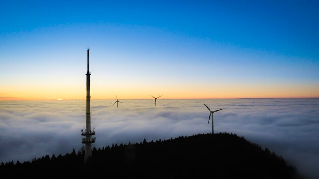 Silhouette of wind turbines against sky during sunset