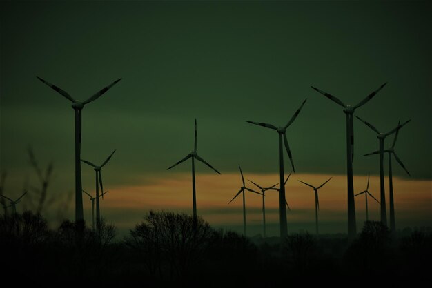 Photo silhouette wind turbines on field against sky during sunset