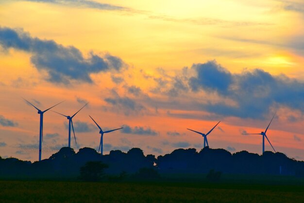 Photo silhouette wind turbines on field against sky during sunset