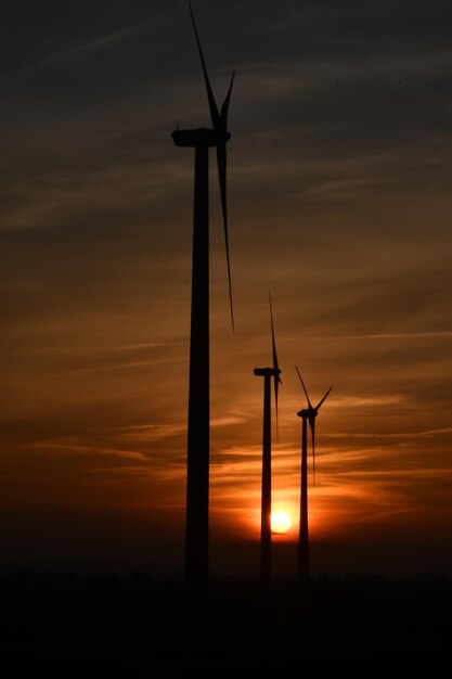 Silhouette windmill on field against sky during sunset