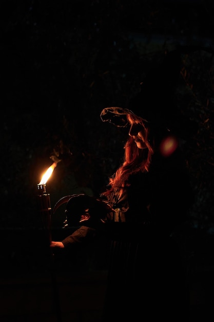 Silhouette of a witch woman with a torch and skull