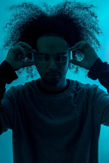 Silhouette with blue light with futuristic led glasses Young man with afro hair on white background