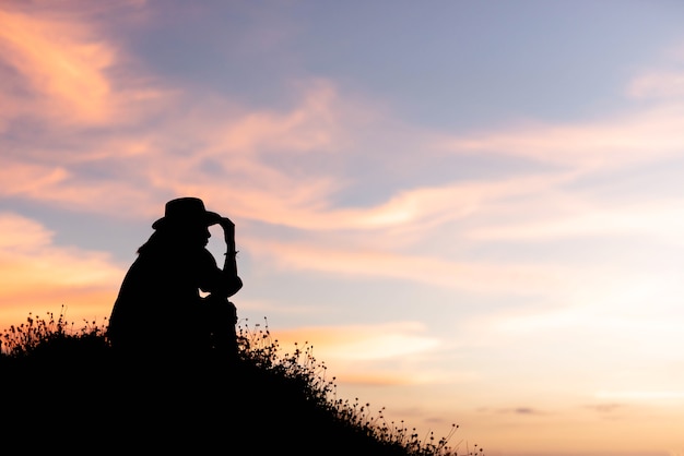 女性のシルエットは、夕日の丘の上にアイデアを使用しています