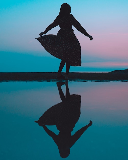 Silhouette woman at beach against sky at night