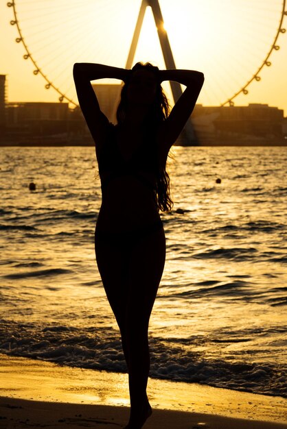 Foto silhouette di una donna sulla spiaggia al tramonto