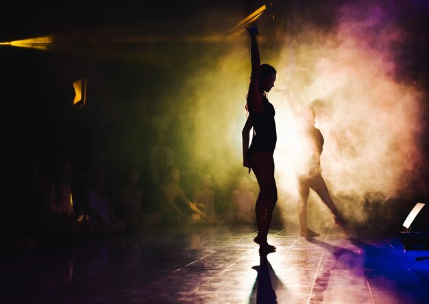 silhouette of a woman dancing between lights and smoke unrecognozible person
