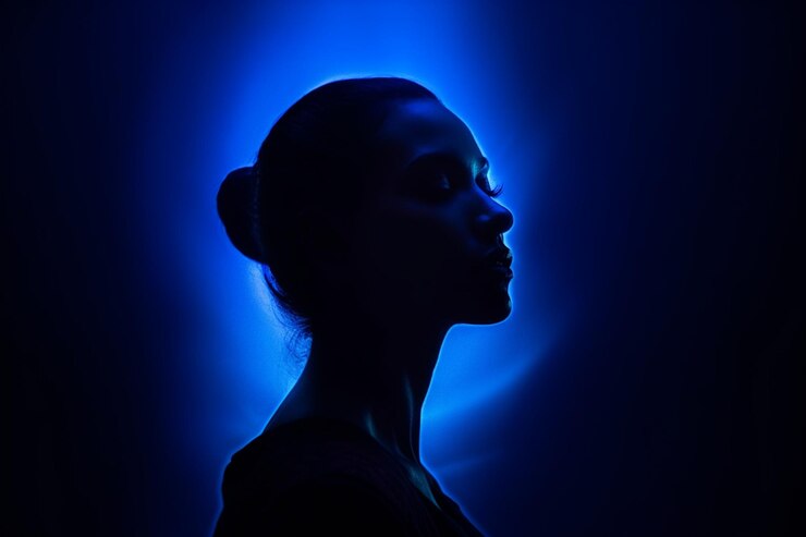 silhouette of woman in the dark with blue light behind