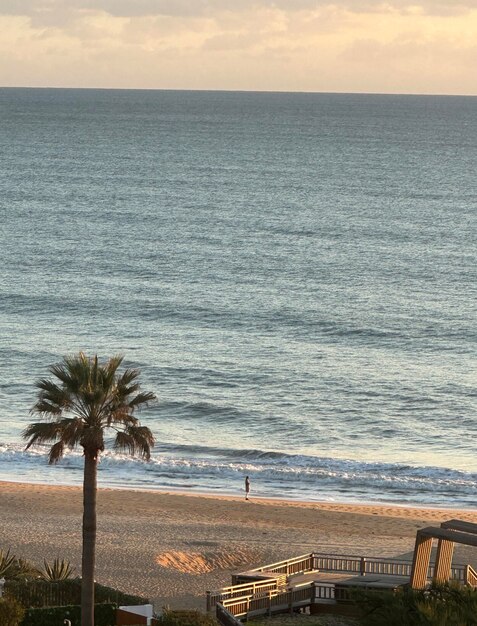 Silhouette of woman in distance along beach at sea