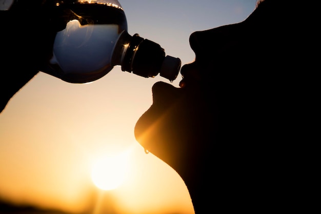 日没時に水を飲む女性のシルエット