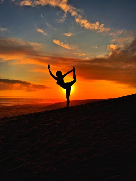 Foto silhouette donna che si esercita sulla spiaggia contro il cielo durante il tramonto