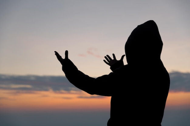 Silhouette of woman hand praying spirituality and religion female worship to god Christianity religion concept Religious people are humble to God Christians have hope faith and faith in god